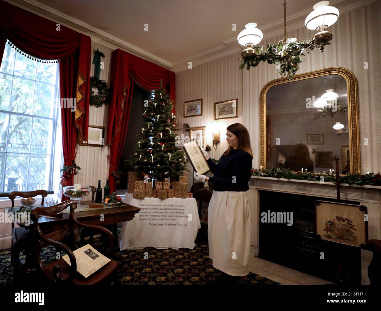 Londra, Gran Bretagna. 16 novembre 2021. Un membro dello staff lavora al Charles Dickens Museum, decorato per Natale, a Londra, Gran Bretagna, 16 novembre 2021. Il Charles Dickens Museum offre un'occhiata a come il Natale è stato celebrato dall'autore vittoriano. Il museo si trova al 48 di Doughty Street, casa di Londra di Dickens dal 1837 al 1839. Mentre viveva in Doughty Street, Dickens finì di scrivere i Pickwick Papers, scrisse Nicholas Nickleby e, più famoso di tutti, Oliver Twist. Credit: Li Ying/Xinhua/Alamy Live News Foto Stock