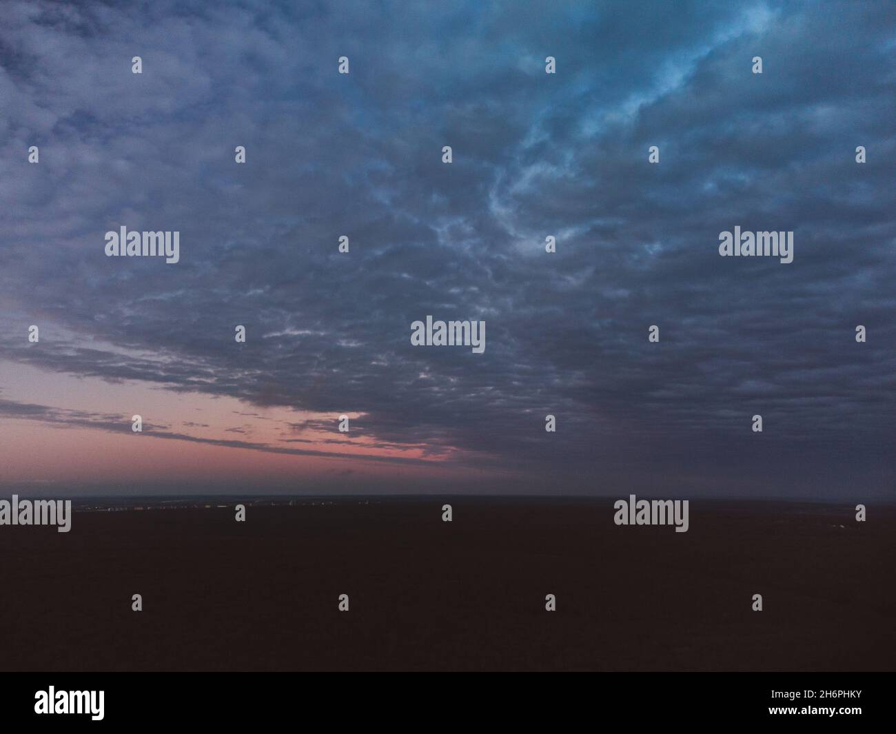 Epica vista aerea del paesaggio nuvoloso scuro sopra la foresta scura al tramonto. Nuvole blu pesanti che coprono la colorata scena del cielo serale Foto Stock