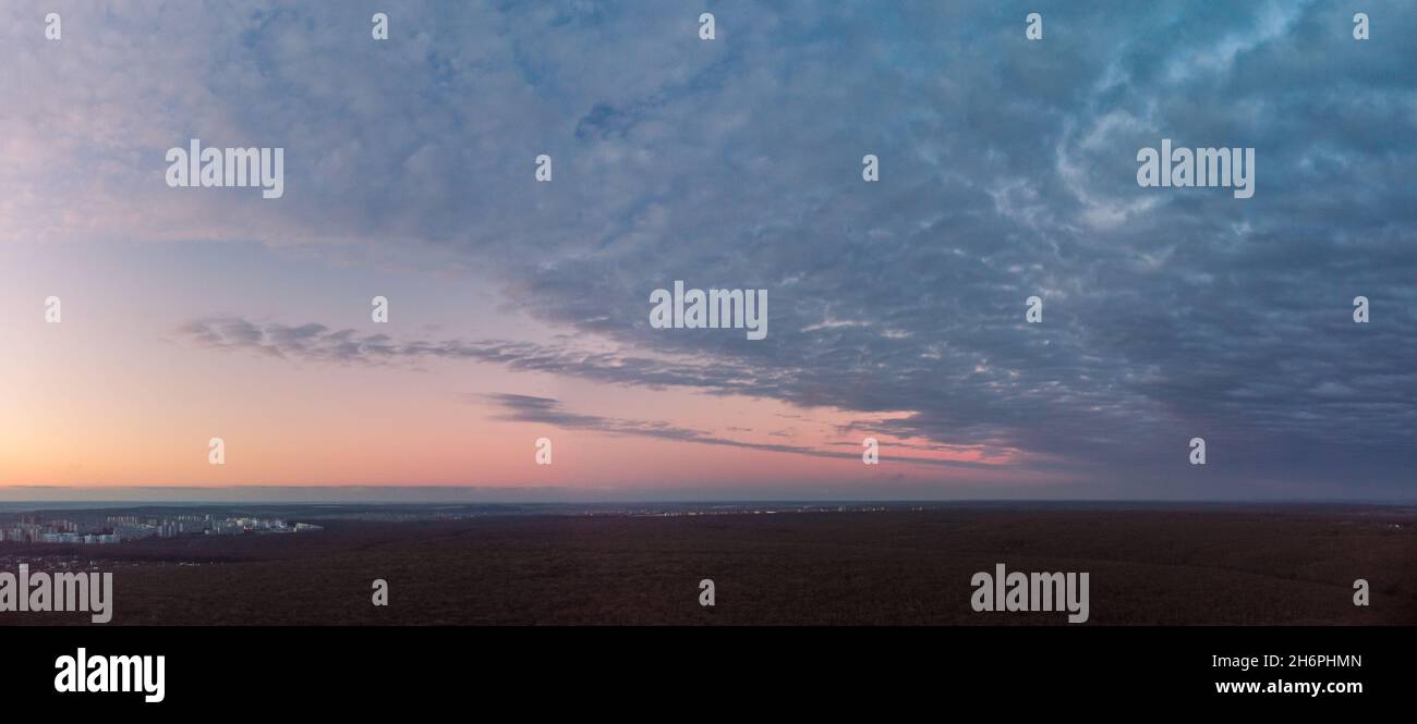 Vista panoramica panoramica aerea, epica e oscura, sopra la foresta scura al tramonto. Nuvole blu pesanti che coprono la colorata scena del cielo serale Foto Stock