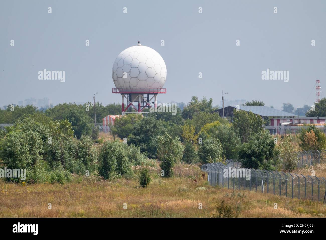 Aeroporto internazionale torre radar a sfera bianca a Kharkiv, Ucraina. Speciale radome a torre a microonde in forma esagonale nel verde Foto Stock