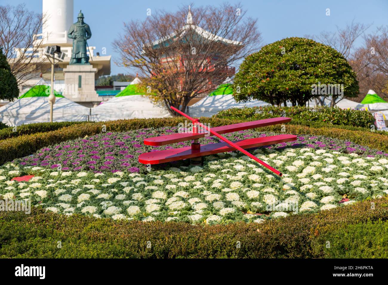 Busan, Corea del Sud - 28 novembre 2015: Orologio floreale sullo sfondo statua di Yi Sun-sin e Busan Tower. Foto Stock