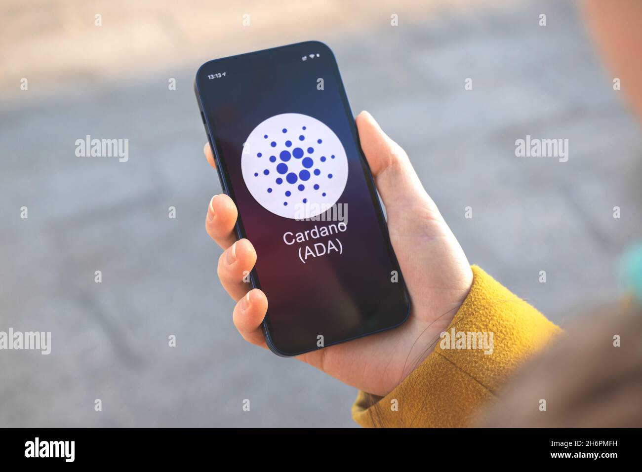 Logo Cardano ADA criptovaluta. Concetto commerciale e finanziario. Mano con smartphone, schermo con icona di crittografia primo piano Foto Stock