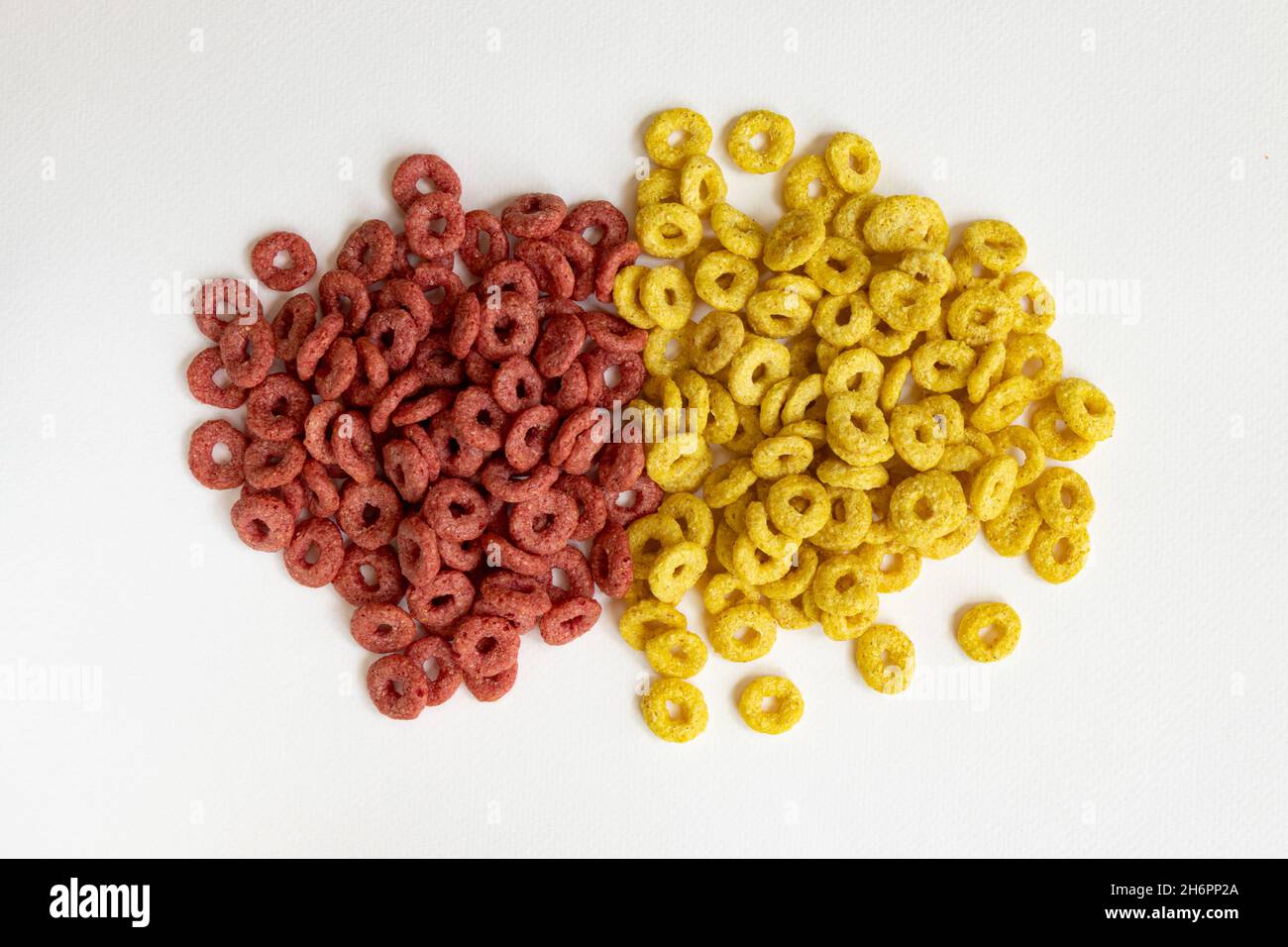 mucchio di cereali di mais zuccherati isolati su sfondo bianco, anelli di mais rosso e giallo Foto Stock