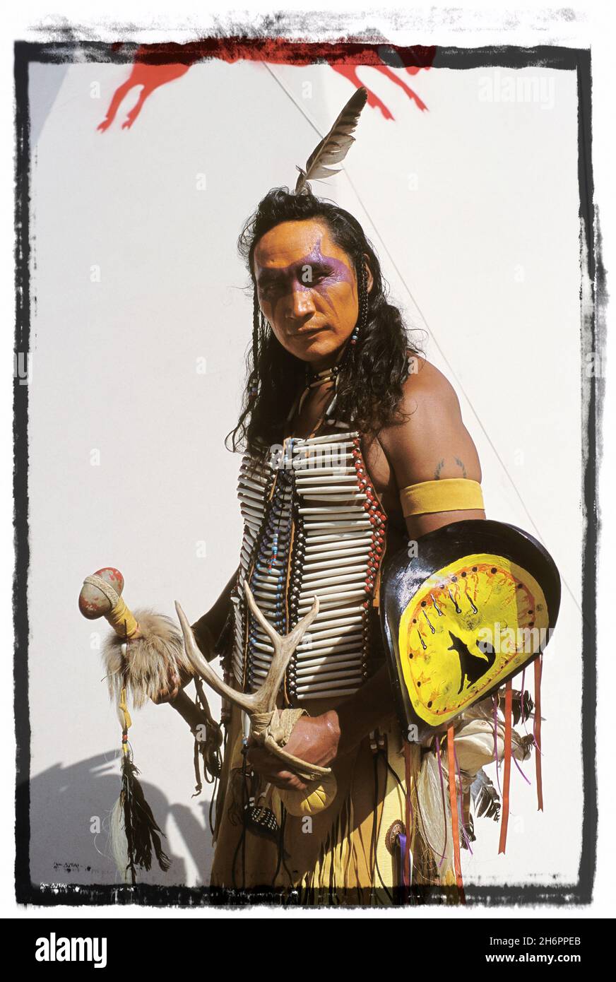 Ritratto di un nativo americano in tradizionale abito cerimoniale in piedi di fronte a un teepee Foto Stock
