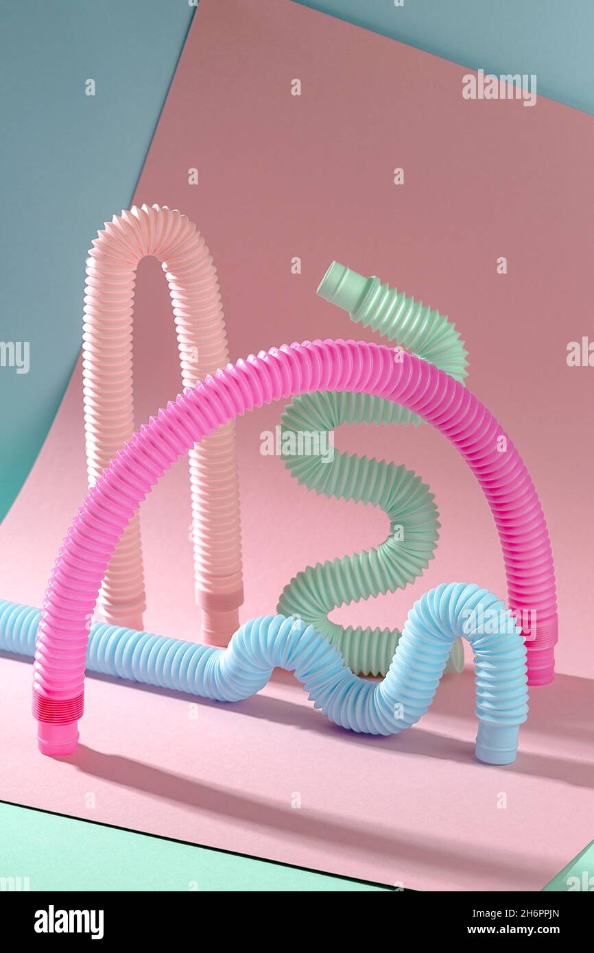 Arco giocattolo rosa antistress tra forme curve su sfondo rosa e blu Foto Stock