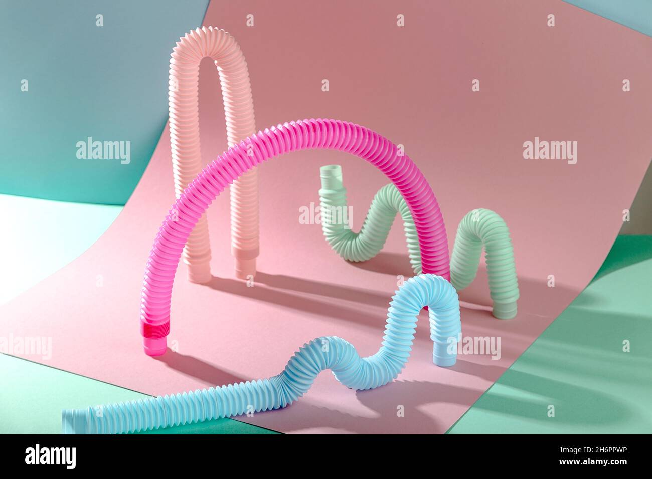 Arco giocattolo rosa antistress tra forme curve su sfondo rosa e blu con spazio per la copia. Foto Stock