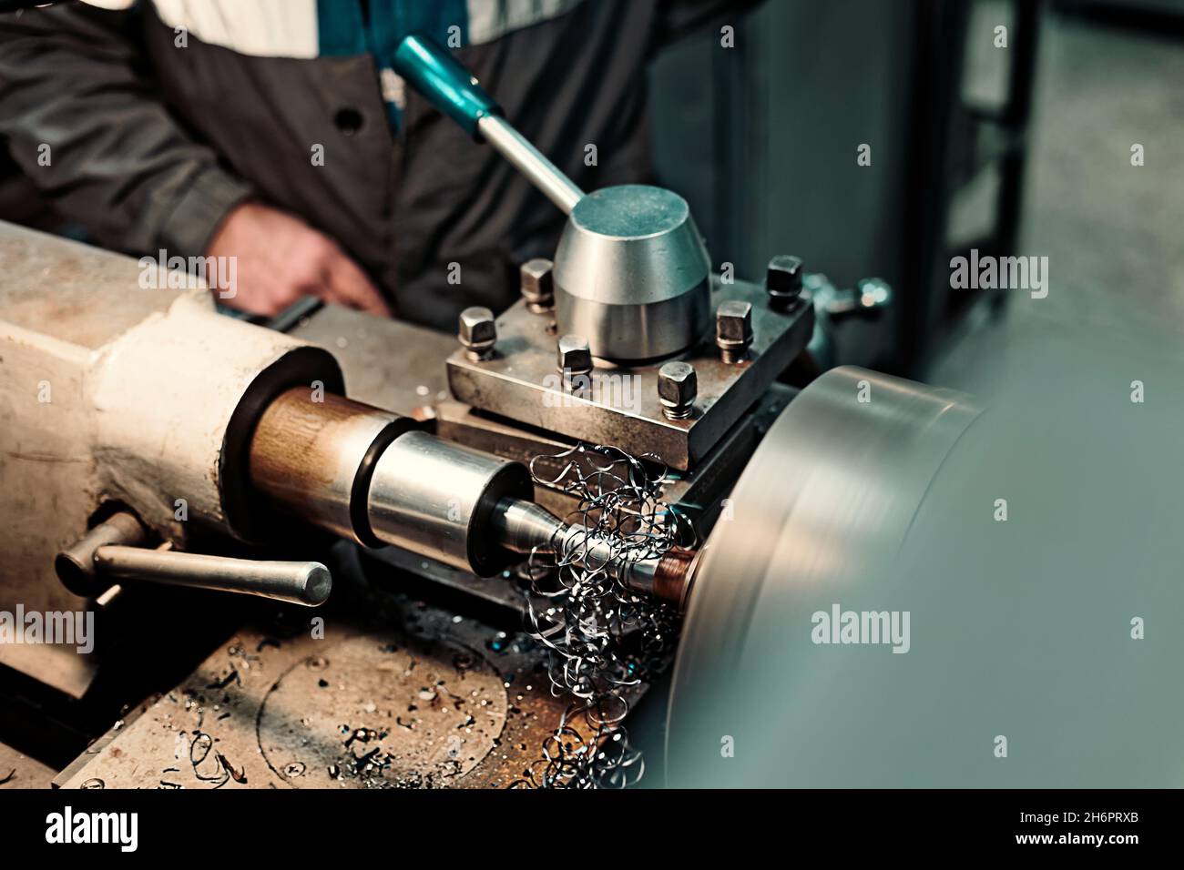 Parte del tornio con taglierina e trucioli metallici in primo piano in officina meccanica. Flusso di lavoro reale in sala di produzione in fabbrica. Luogo di lavoro di Turner. Sfondo. Foto Stock