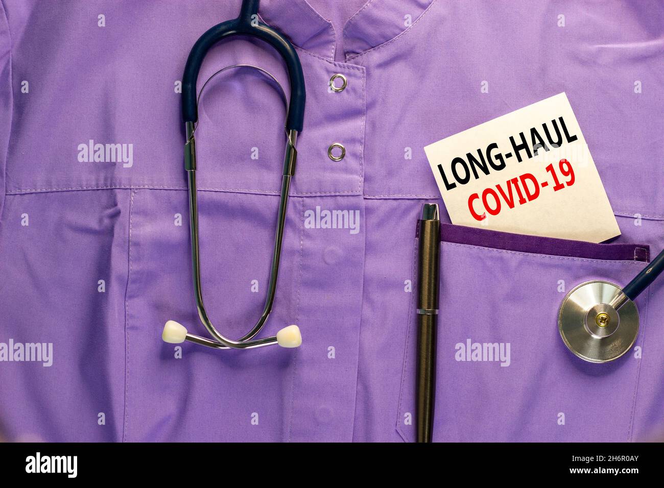 COVID-19 simbolo dei sintomi del codice a lunga distanza. Carta bianca con parole Long-haul covid-19. Uniforme medica, penna metallica e stetoscopio. Medico, COVID-19 lo Foto Stock