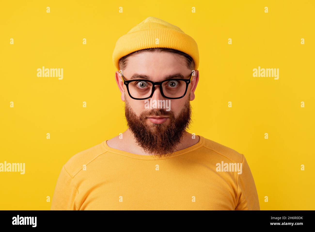 uomo con pazzo sguardo su sfondo giallo, ragazzo bearded guardando in macchina fotografica Foto Stock