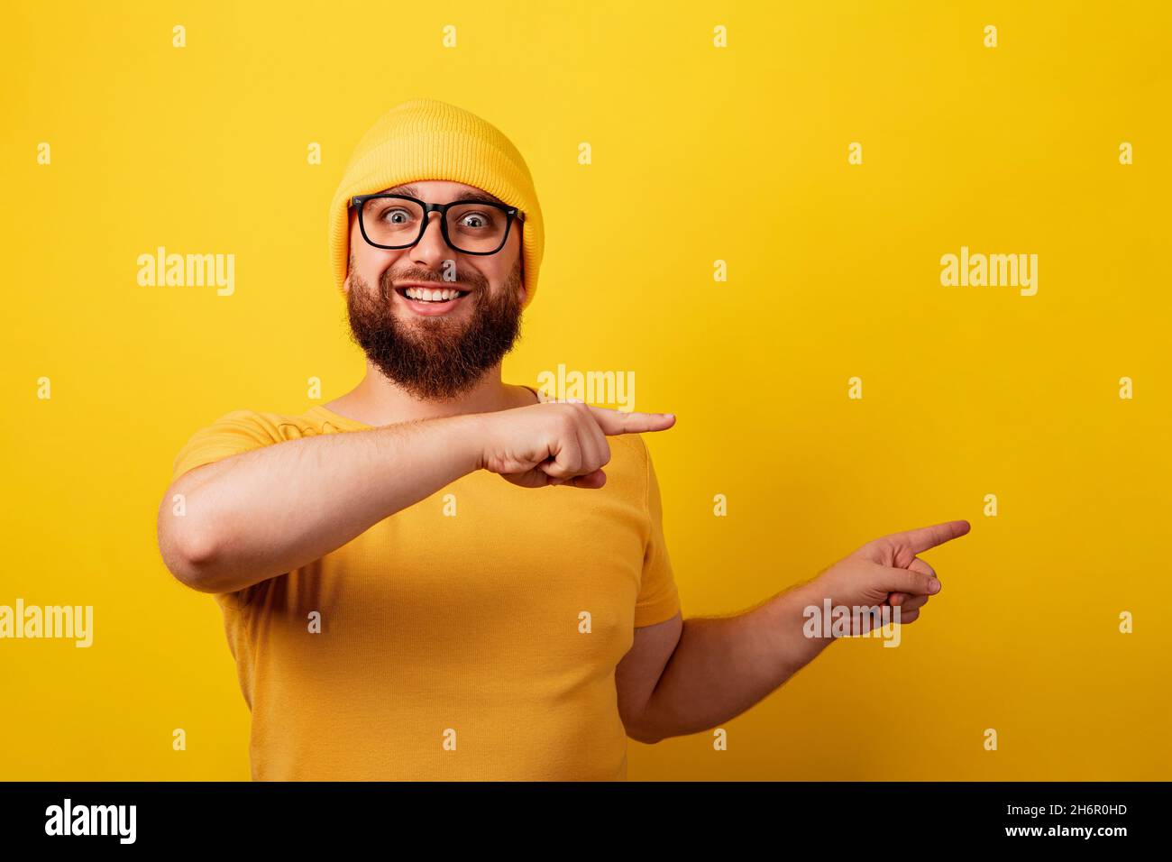 uomo sorridente con bearded in occhiali puntano le dita su sfondo giallo Foto Stock