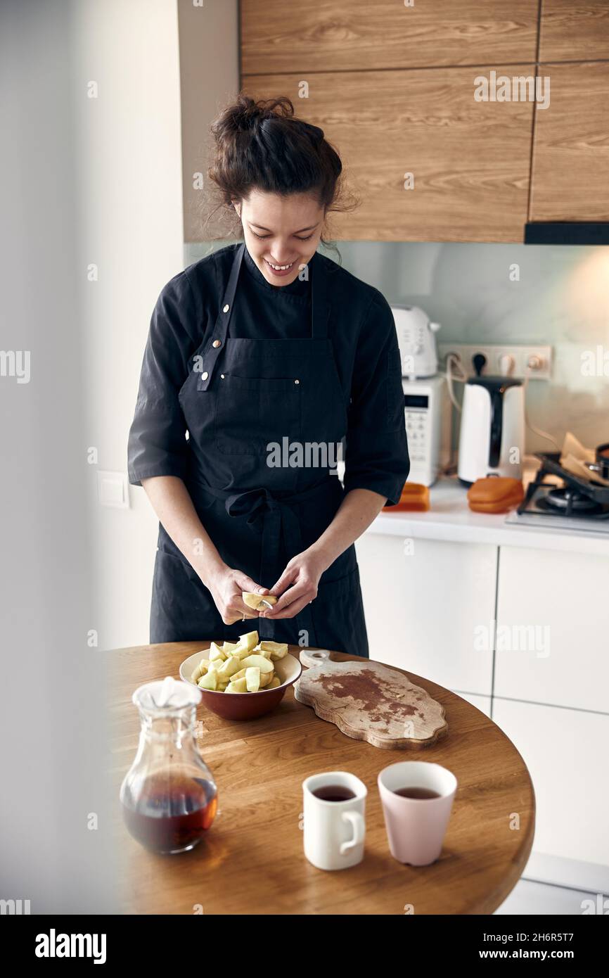 bella donna mediorientale che prepara le mele per cucinare all'accogliente cucina stillish Foto Stock