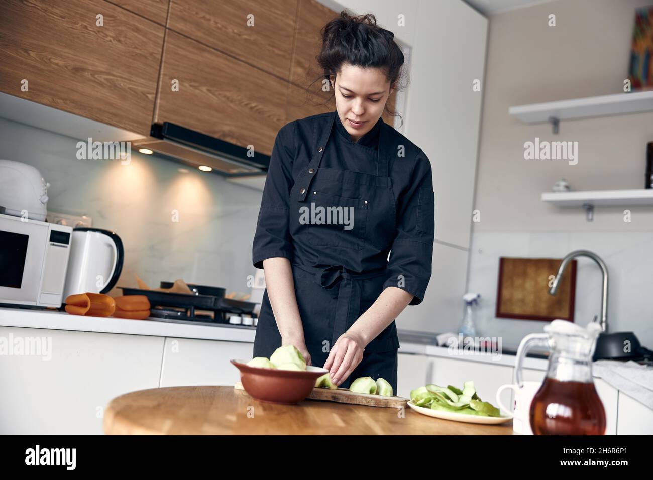 bella donna mediorientale che prepara le mele per cucinare all'accogliente cucina stillish Foto Stock