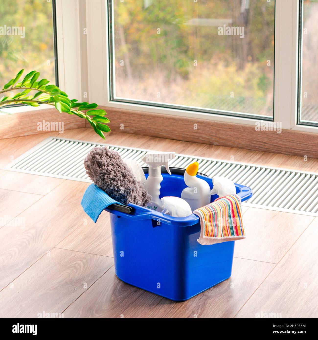 Detergente per la casa su pavimento in legno su sfondo finestra Foto Stock