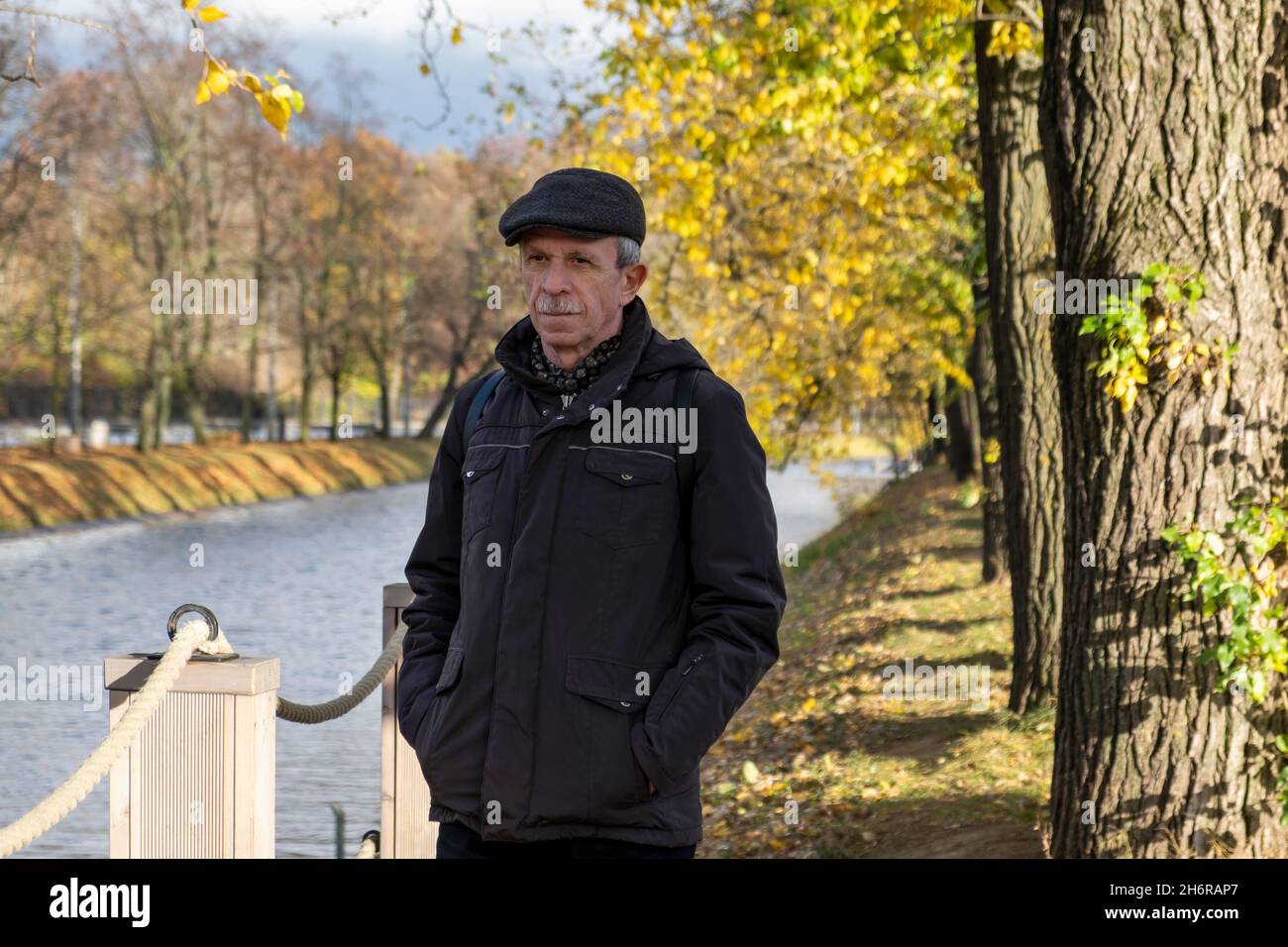 Anziano pensionato si trova in una bella giornata d'autunno nel parco cittadino Foto Stock