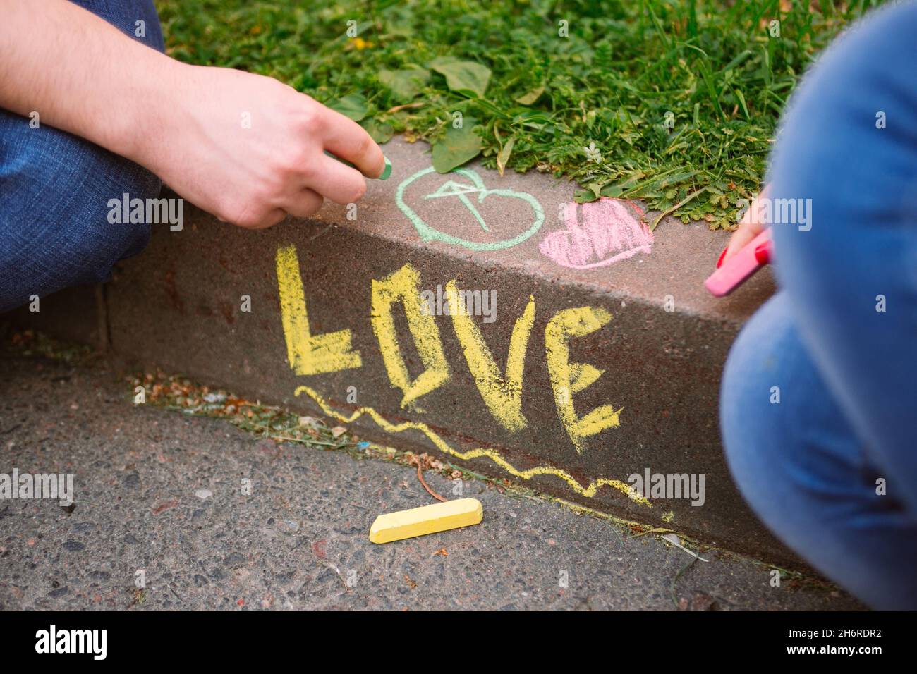 La parola amore scritto in gesso sul marciapiede e le mani della coppia che  disegnano con gesso Foto stock - Alamy
