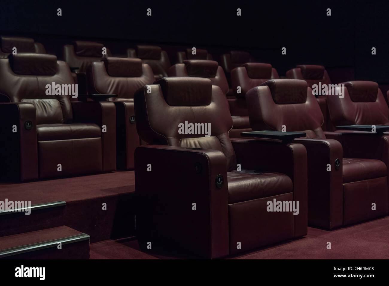 file di poltrone in pelle marrone in una sala cinema vuota in un cinema durante la quarantena del coronavirus. Foto Stock