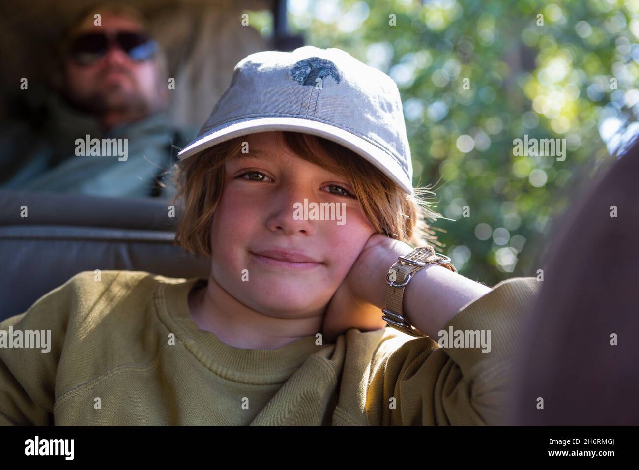 Un ragazzo seduto in una jeep poggiato sul gomito in una jeep safari. Foto Stock