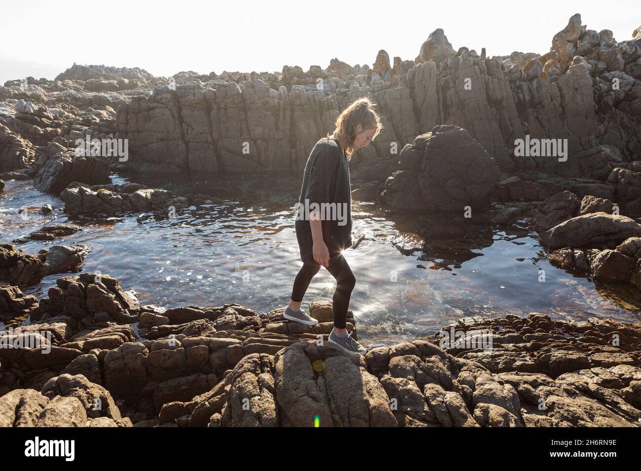 Ragazza adolescente che cammina attraverso rocce frastagliate, esplorando piscine di roccia vicino all'oceano Foto Stock