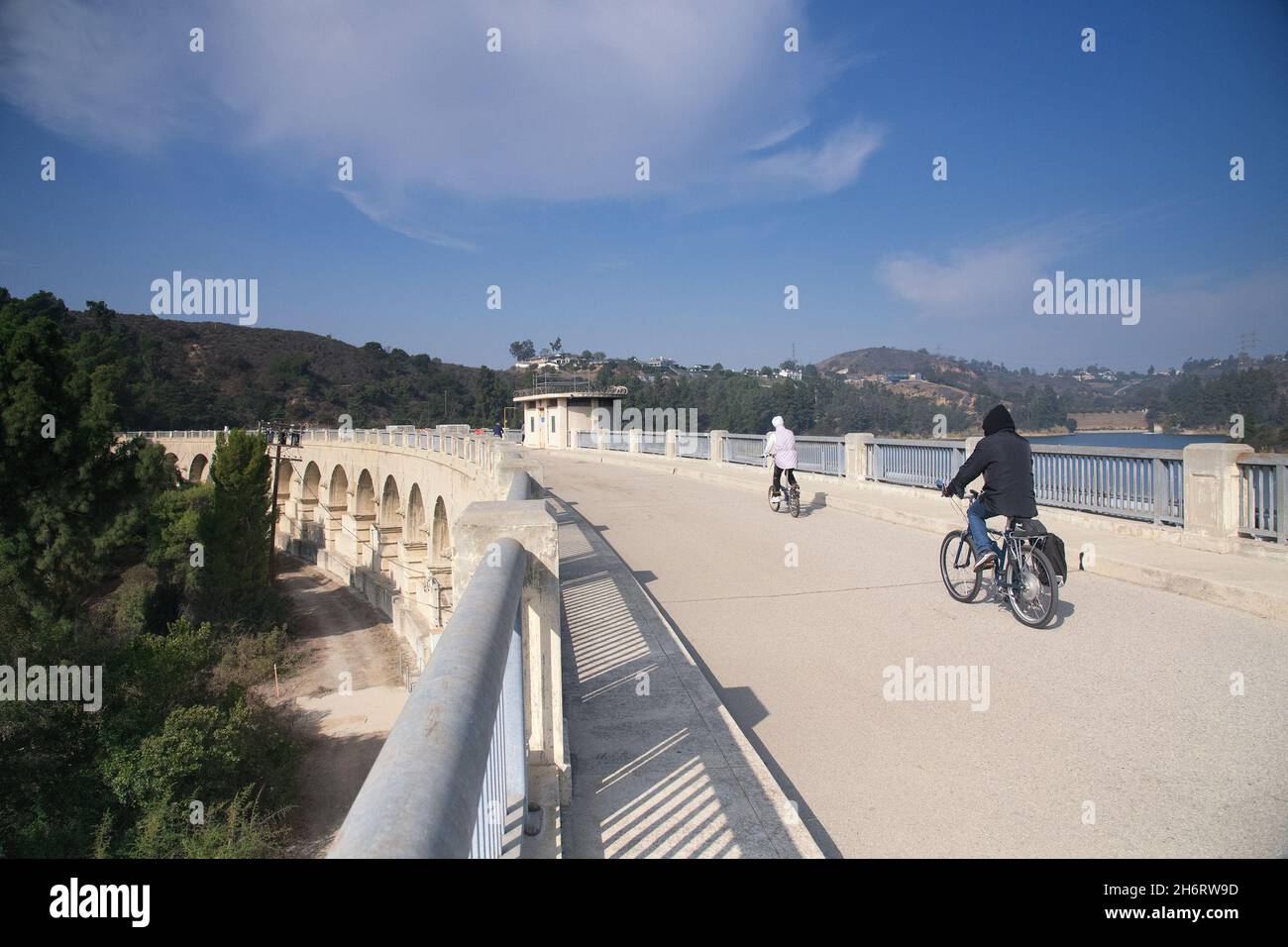 Los Angeles, CA, USA - November17, 2021: Due ciclisti attraversano il lago Hollywood attraverso la diga di Mulholland a Los Angeles, CA. Foto Stock