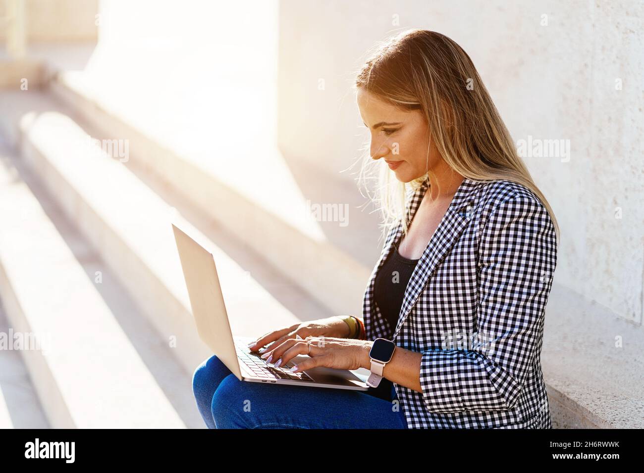 Donna sorridente che naviga su un notebook per strada Foto Stock