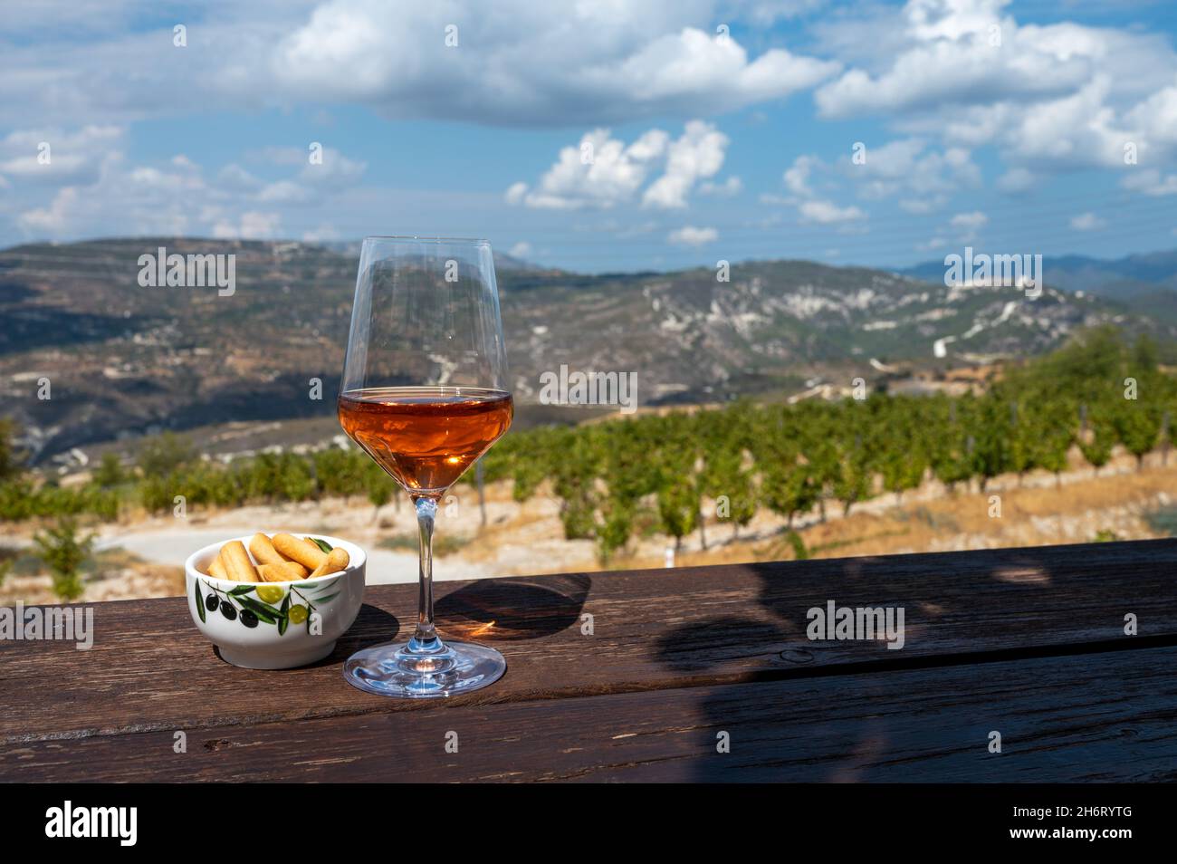 Industria del vino dell'isola di Cipro, degustazione di vino secco di rose in cantina con vista sui vigneti e le pendici meridionali della catena montuosa di Troodos in giornata di sole Foto Stock