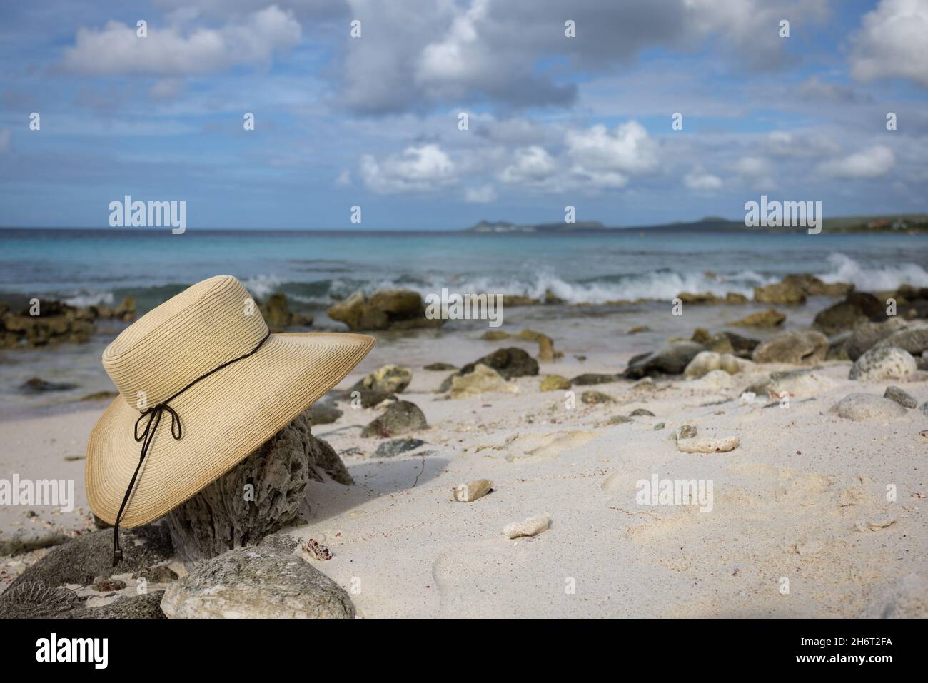 Cappello di paglia adagiato sulla spiaggia di sabbia con coralli. Stagcape. Foto Stock