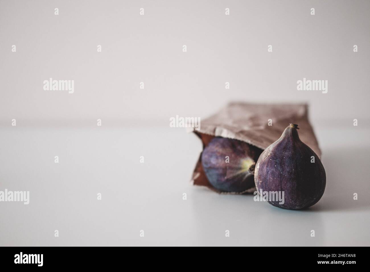 Raccolta di frutta fresca di fichi interi maturi in carta artigianale marrone. Cibo biologico. Minimalismo, spazio di copia Foto Stock
