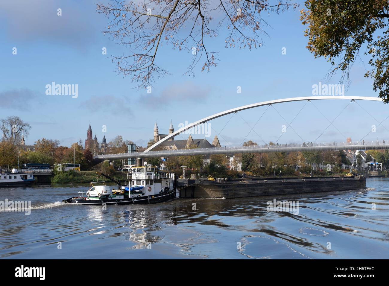 Spingere o rimorchiatore con un'auto sul retro spinge un pontile non semovente caricato o chiatta attraverso il Maas sotto il ponte 'Hoge Brug' a Maastricht Foto Stock