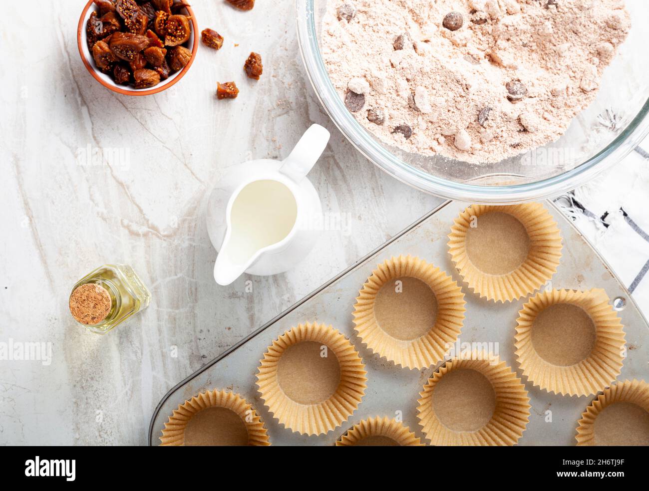 Immagine della vista dall'alto che mostra la preparazione di deliziosi cupcake di frutta e noci su sfondo bianco del piano di lavoro in marmo. Lattina di muffin con liner, ingredienti, e utensi Foto Stock