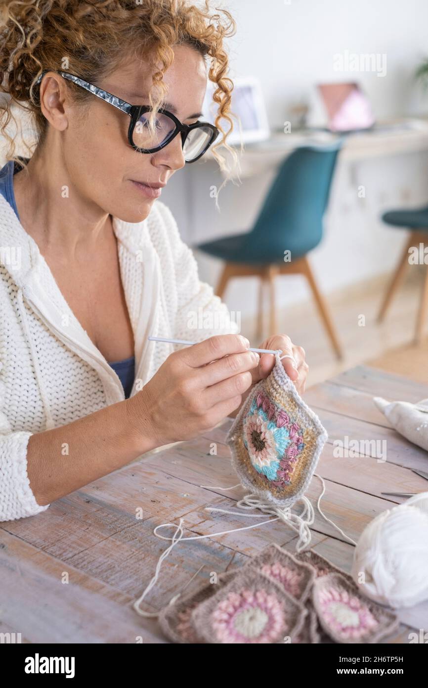 Donna adulta attraente a casa occupato in un hobby crochet lana attività di svago e lavoro alternativo. Moderna donna amore fatto a mano e artigianato beautiffu Foto Stock