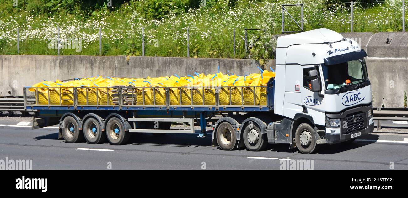 Vista laterale catena di fornitura bianca rimorchio autocarro hgv caricato con grandi sacchi di fibre gialle di materiali da costruzione sfusi sfusi in autostrada UK Foto Stock