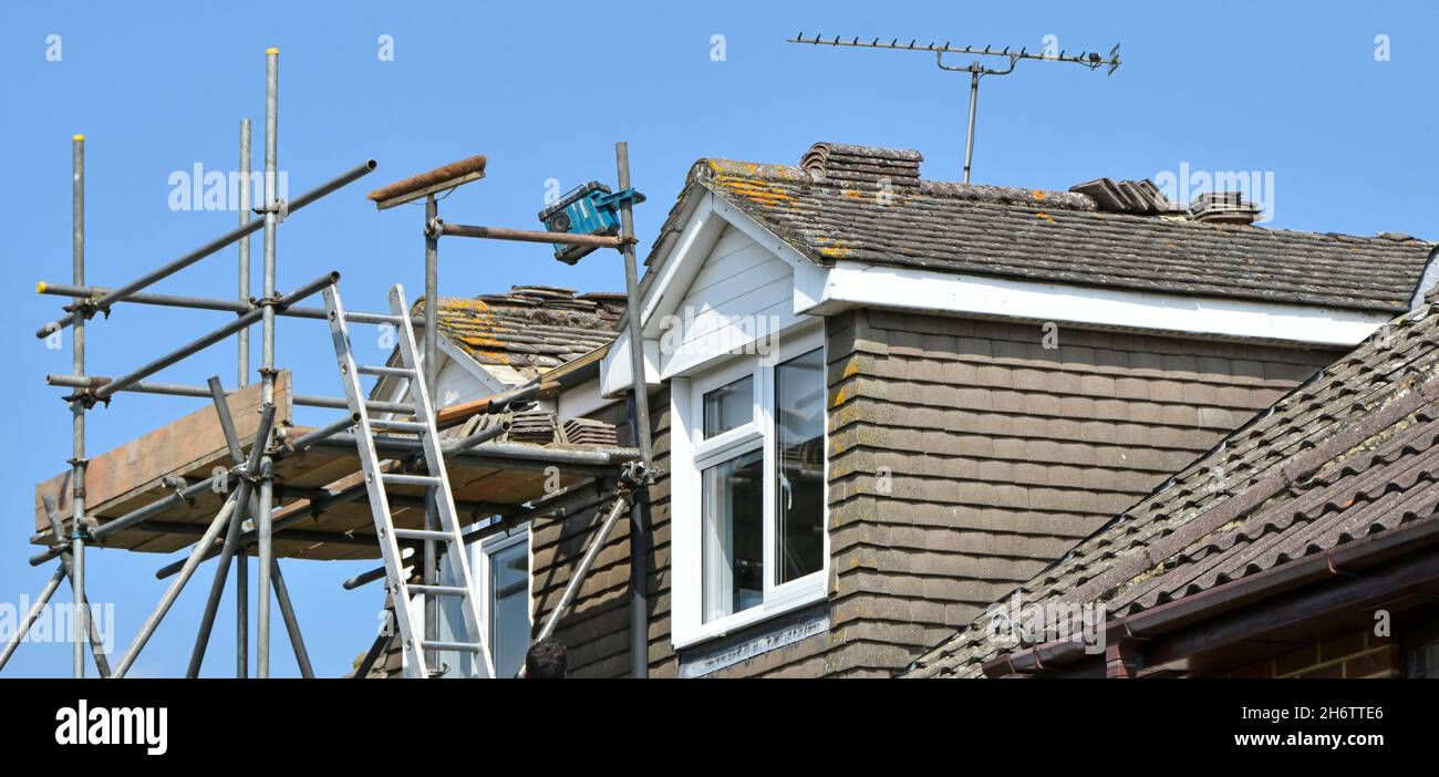 Costruttori ponteggi torre intorno dormer camere per l'accesso sicuro scala alla riparazione di manutenzione del tetto e rimontare tegole di colmo del tetto semplice per casa Inghilterra UK Foto Stock