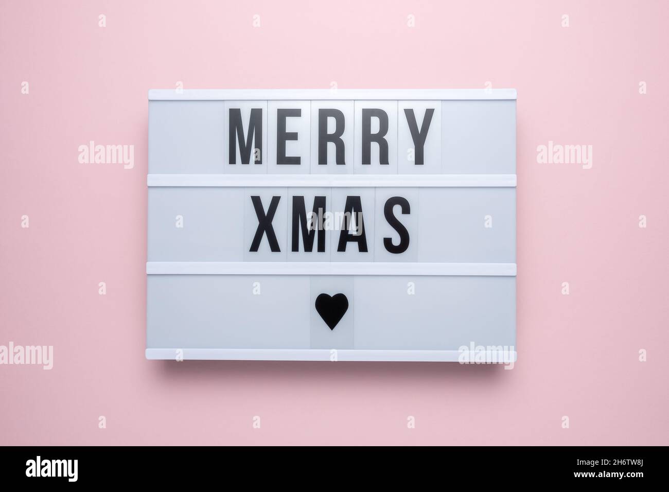 Scatola luminosa con il testo ALLEGRO XMAS su sfondo rosa. Minimo Natale o Capodanno concetto. Foto Stock