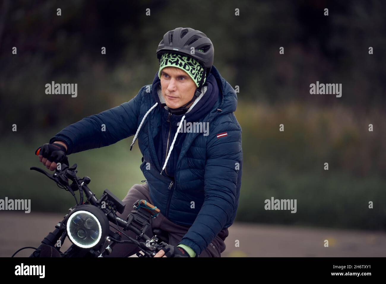 19-09-2021 riga, Lettonia ciclista europea seria e concentrata che indossa abiti da ciclismo neri, casco, occhiali e guanti che cambiano velocità Foto Stock