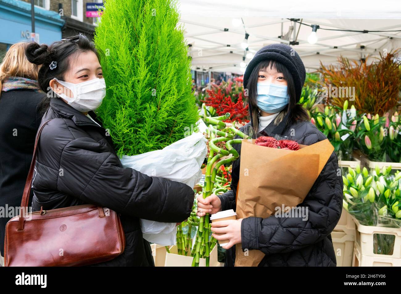 Columbia Road Flower Market giovani donne giapponesi piante fiori in strada al mercato bancarelle Domenica di Novembre 2021 East London UK KATHY DEWITT Foto Stock