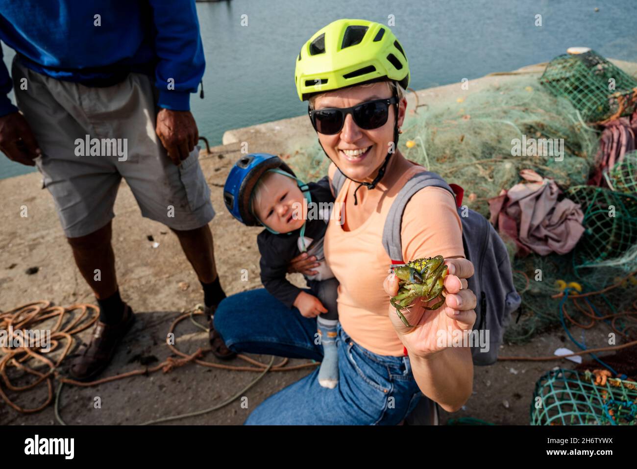 Una donna turistica ama tenere un granchio verde in mano nel porto di Alvor, Algarve, Portogallo Foto Stock