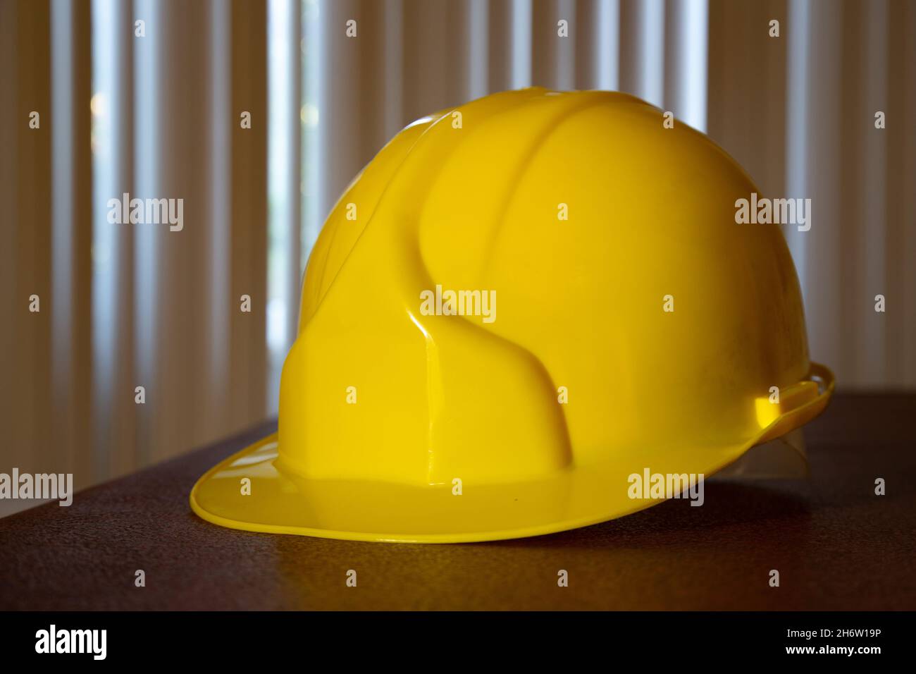 Casco di sicurezza giallo sul tavolo. Vista frontale del casco di sicurezza giallo. Foto Stock