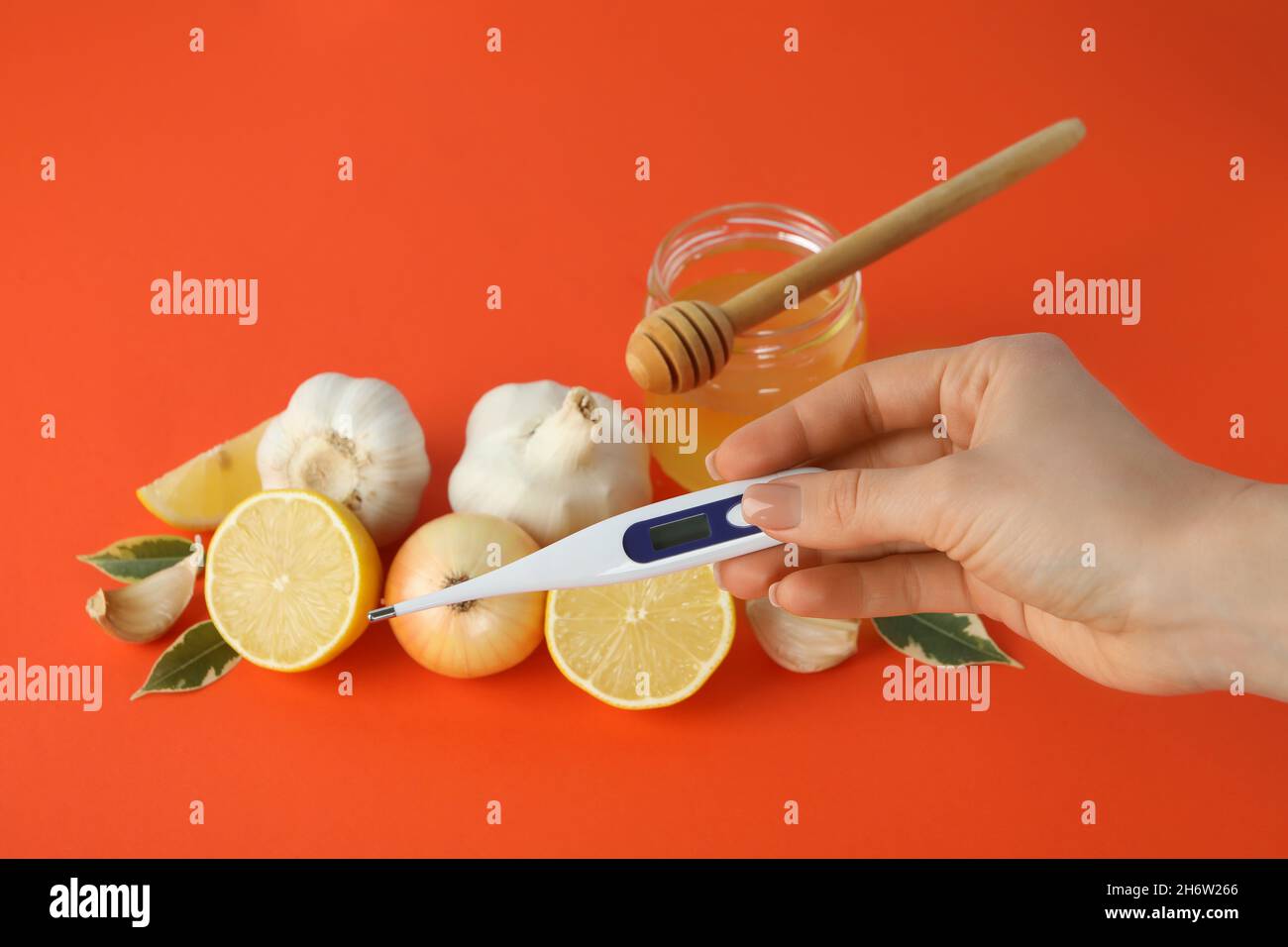 Concetto di trattamento del raffreddore con miele e aglio su sfondo arancione. Concetto di trattamento del raffreddore con miele e aglio su arancione Foto Stock