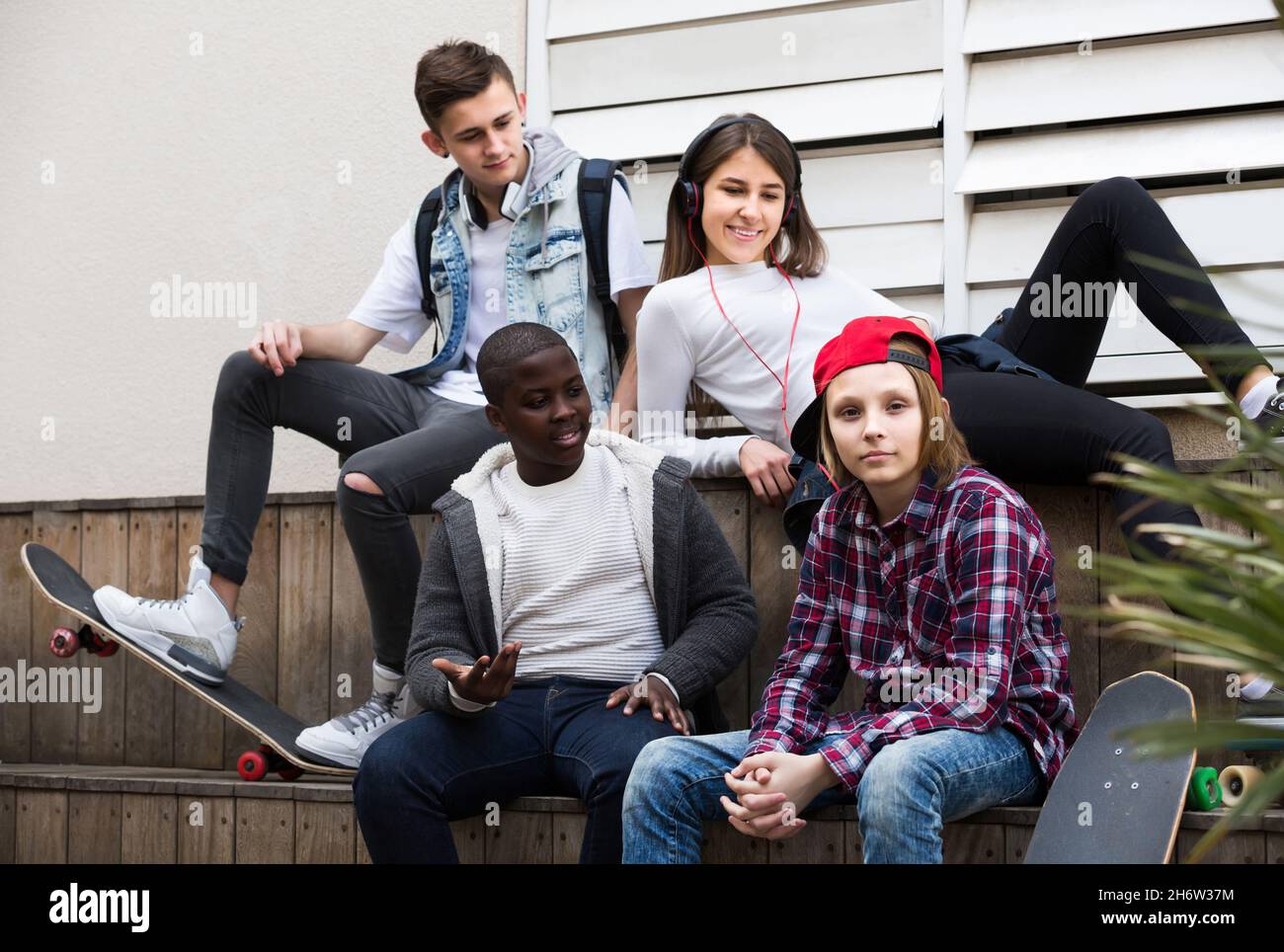 ragazza e tre ragazzi che si stendono fuori all'aperto e discutere qualcosa Foto Stock