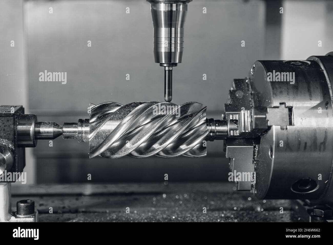 La fresatrice CNC industriale lavora la parte di vite senza fine in acciaio con trucioli metallici. Foto Stock