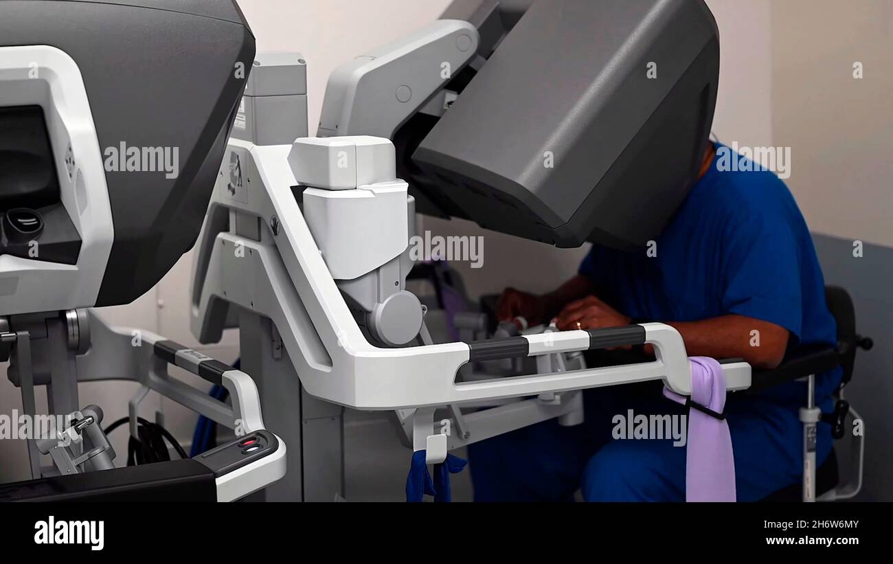 primo piano di un medico o di un chirurgo che manipola un robot chirurgico per eseguire un'operazione in una sala operatoria Foto Stock