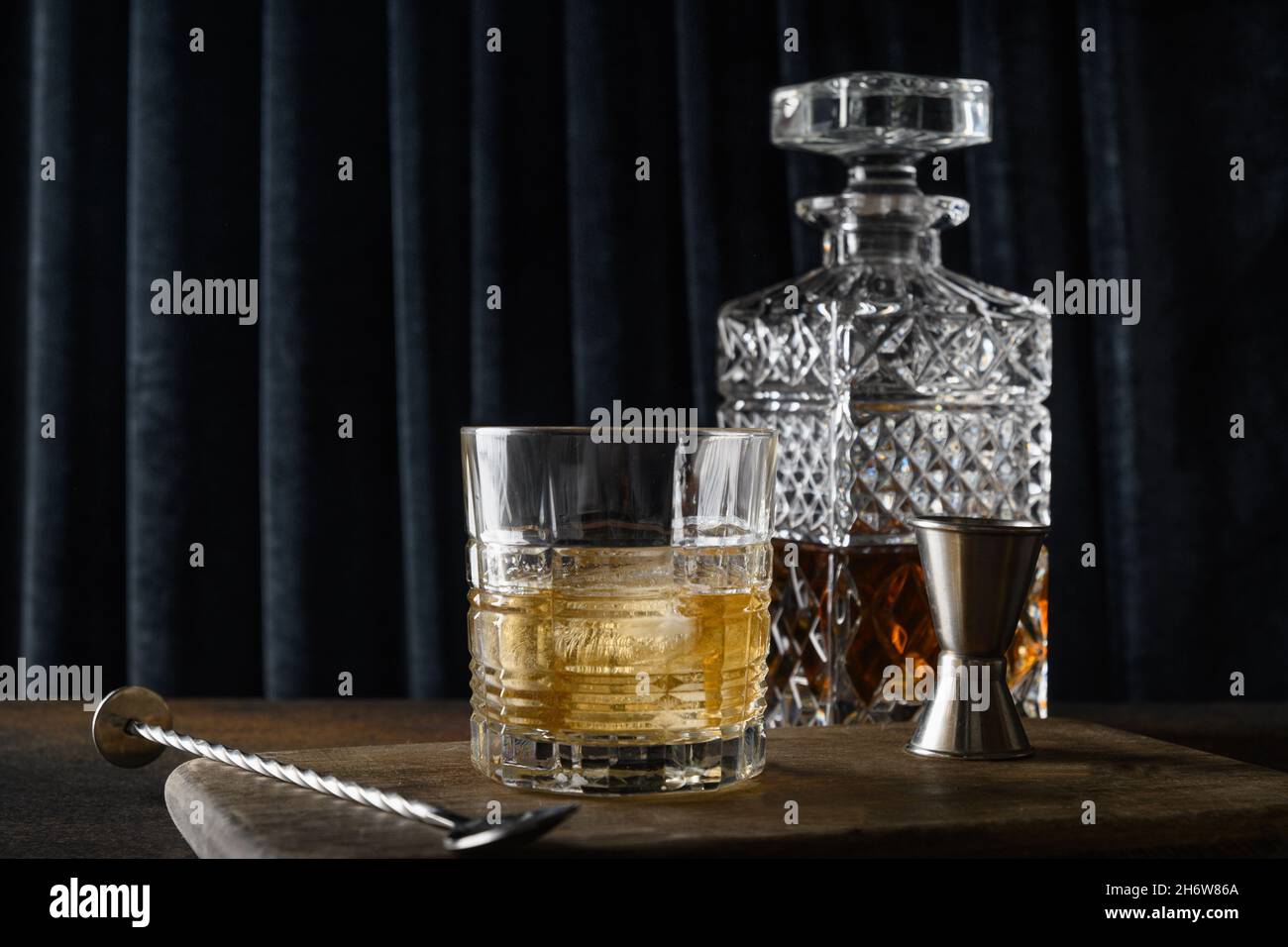 Whiskey in rocce e bottiglia su sfondo scuro tenda blu. Festa di festa. Foto Stock