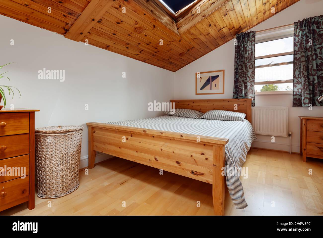 Cambridge, Inghilterra - Agosto 21 2019: Camera da letto mansardata in una casa vittoriana con letto matrimoniale e soffitto in pannelli di legno Foto Stock