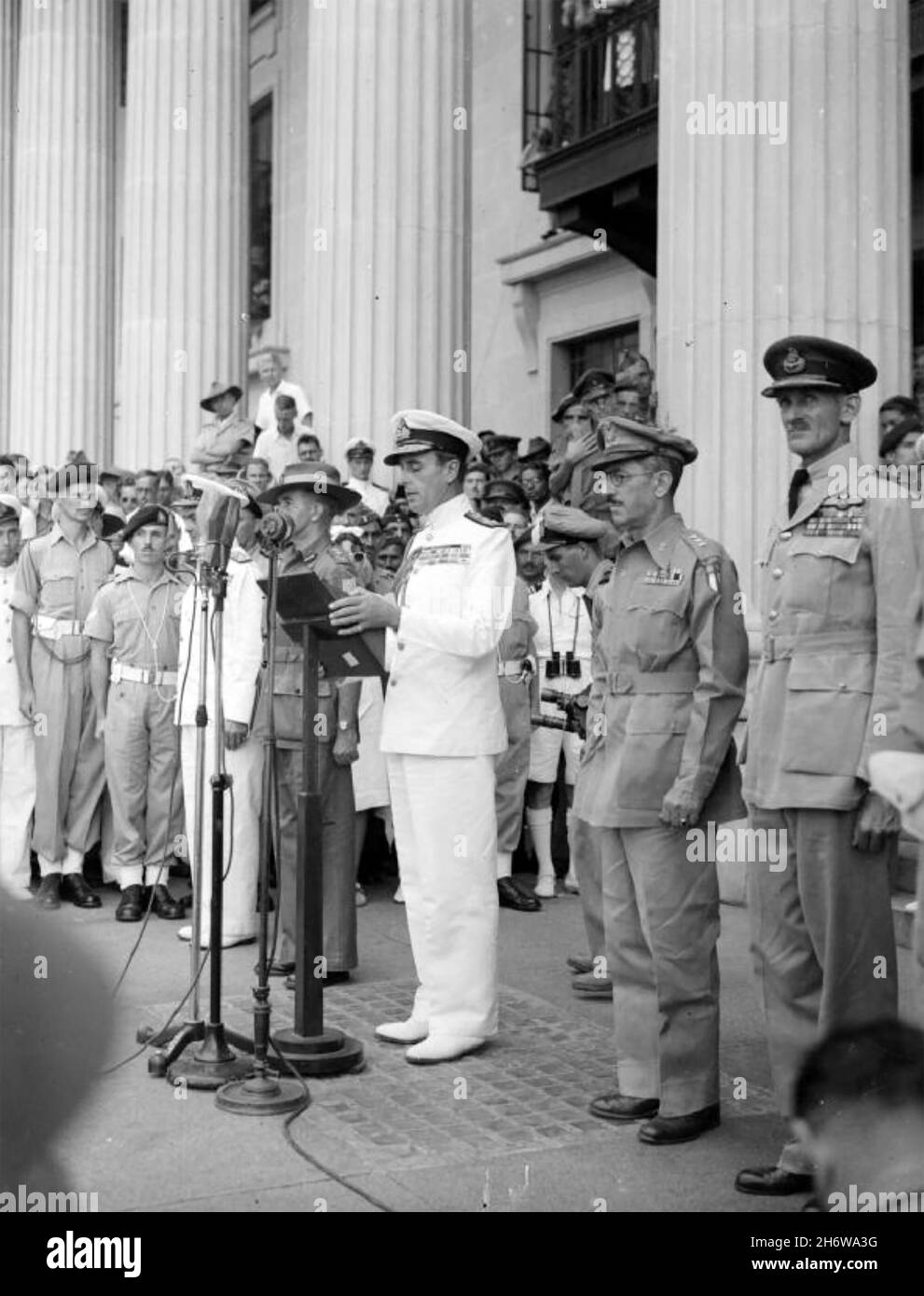 LOUIS MOUNTBATTEN, 1° conte Mountbatten di Birmania (1900-1979) ufficiale della Royal Navy e statista che fa un discorso al Palazzo Municipale di Singapore nel gennaio 1945 dopo la resa giapponese. Alla sua destra c'è il generale William Slim in cappello slouch, alla sua sinistra il tenente generale Wheeler dell'esercito degli Stati Uniti e l'alto personaggio del maresciallo Air Chief Sir Keith Park, Foto Stock