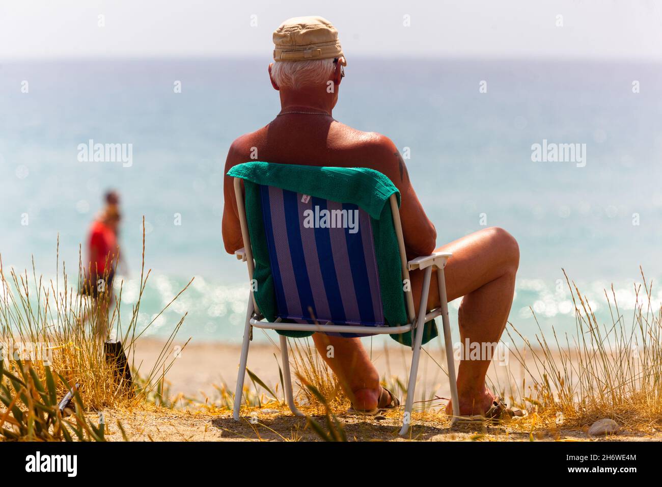 Vecchio turista sdraio in spiaggia per rilassarsi sul retro Foto Stock