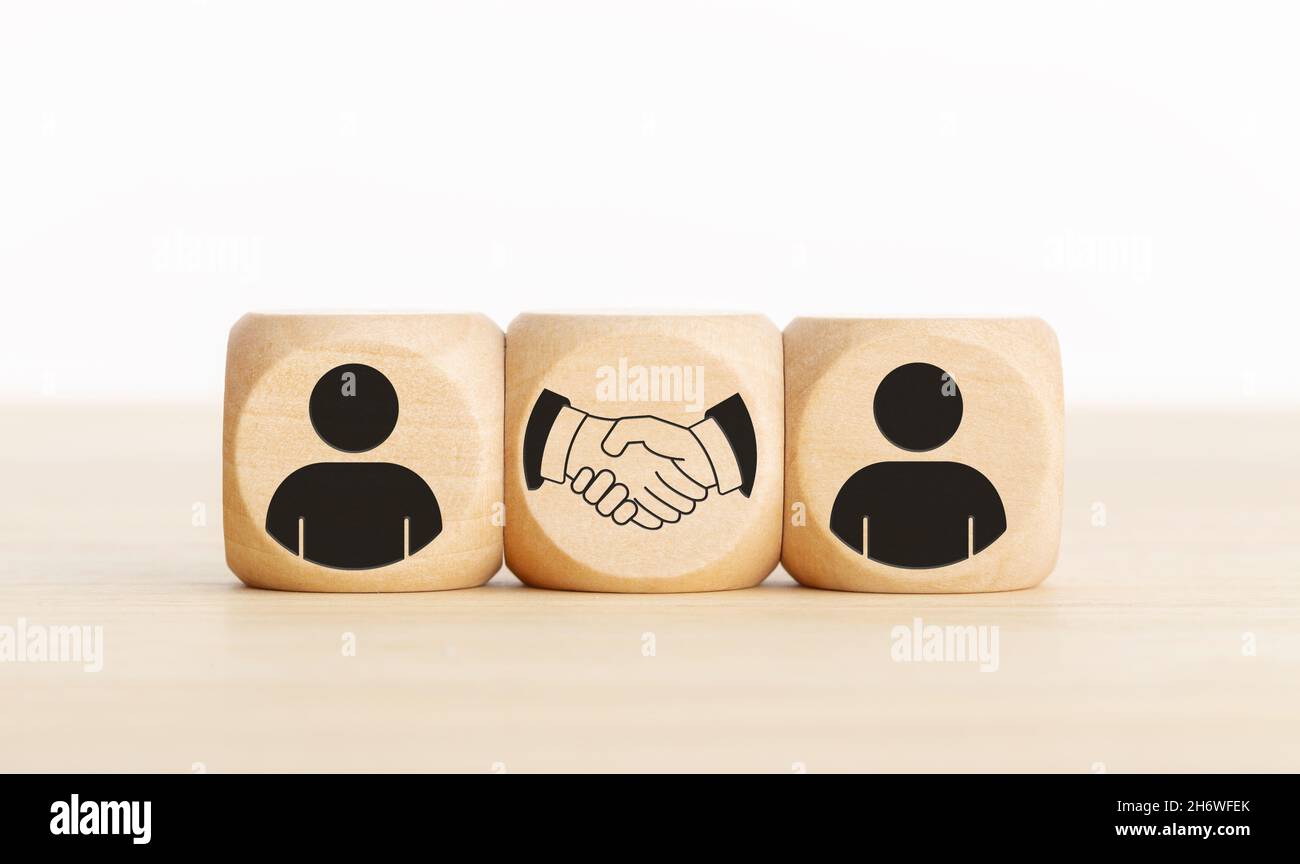 Accordo, partnership o accordo. Icone di persone e di handshake su blocchi di legno. Spazio di copia Foto Stock