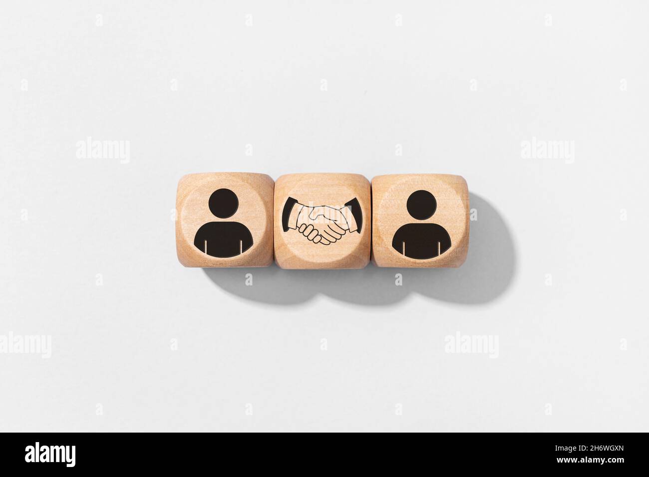 Accordo, partnership o accordo. Icone di persone e handshake su blocchi di legno isolati su sfondo grigio Foto Stock