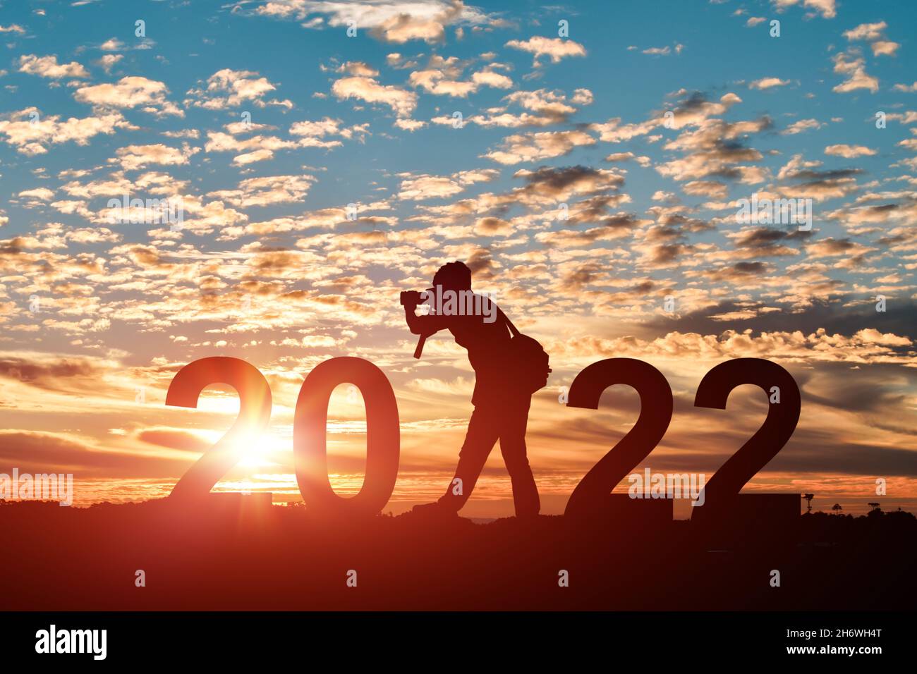 Silhouette del fotografo che scatta foto in 2022 anni all'alba o al tramonto. Idea per felice anno nuovo 2022. Foto Stock