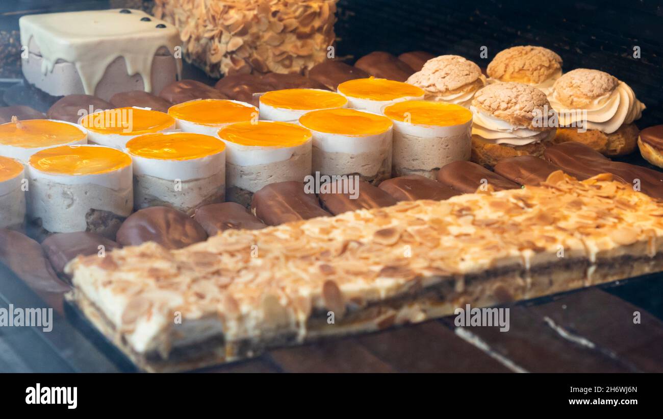 Diversi tipi di torte in una pasticceria display in vetro Foto Stock