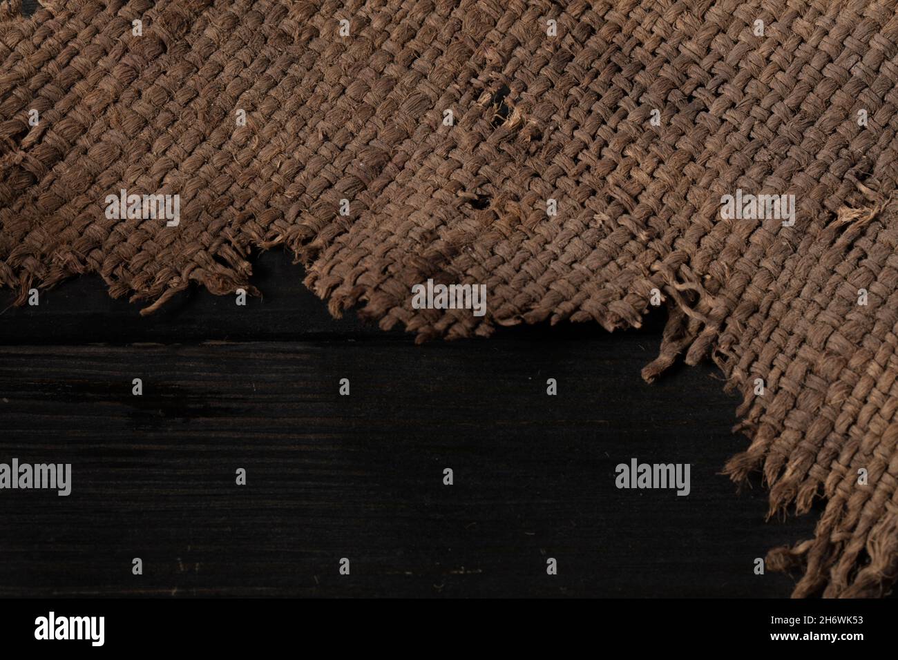 Primo piano di sovrapposizione. Tela ruvida. Tessuto di tessitura ruvido su sfondo di legno. Foto Stock